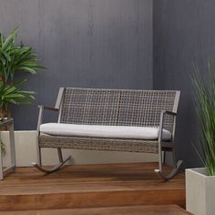 a metal bench sitting on top of a hard wood floor next to potted plants