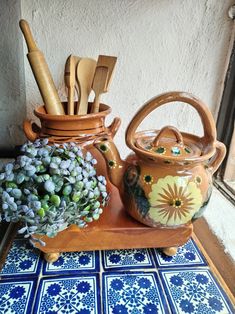 an assortment of kitchen utensils are sitting on a table next to a potted plant