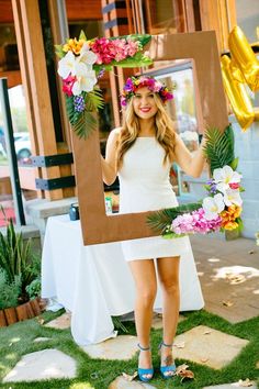 a woman is standing in front of a photo frame with flowers on her head and wearing sandals