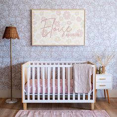 a baby's crib in front of a floral wallpaper with the name flore on it