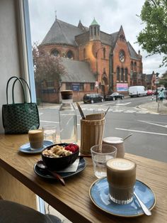 two cups of coffee sit on a table near a window with a view of the street