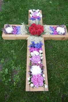 a wooden cross with flowers on it in the grass