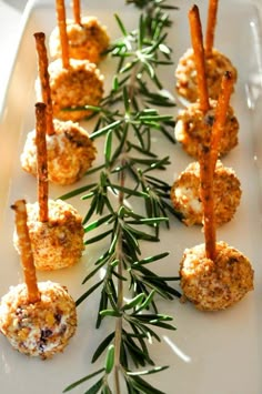 appetizers are arranged on a white plate with green sprigs and rosemary