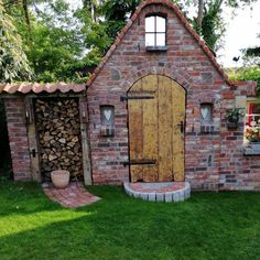 a small brick building with a wooden door and window on the outside, surrounded by green grass