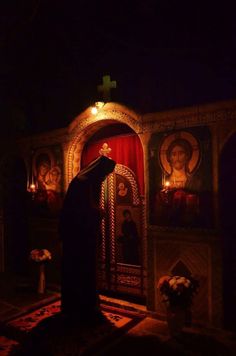 a person standing in front of a church with paintings on the wall and candles lit