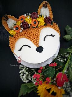 a cake decorated to look like a fox with flowers on its head and eyes closed