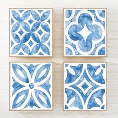 four blue and white wall art pieces hanging on the wall