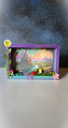 a small purple frame with a painting on it and flowers in the corner next to it