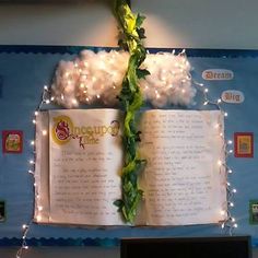 an open book with lights on it hanging from the ceiling in front of a bulletin board