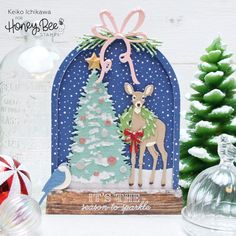 there is a christmas card with a deer and tree in the front, on top of a table