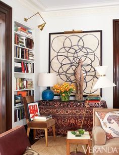 a living room filled with furniture and bookshelves next to a painting on the wall