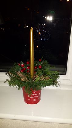 a candle is sitting in a red container on a window sill