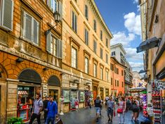 many people are walking down the street in front of buildings and shops on both sides