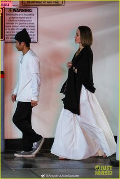 a man and woman are walking down the street in long white dresses with black shoes