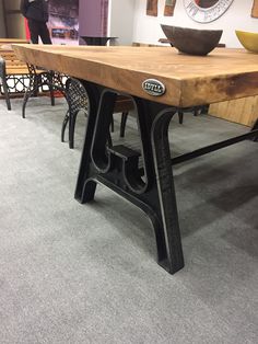 a wooden table with metal legs on display in a room filled with tables and chairs