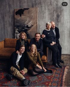 a group of people sitting on top of a rug in front of a wall with paintings