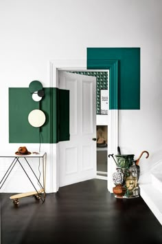 an open door in a room with green and white decor on the walls, along with a small table