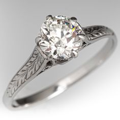 an antique style diamond ring with filigree leaves on the band and center stone