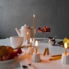 the table is set with candles, fruit and teapots for afternoon tea party