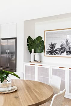 a dining room table with chairs and a refrigerator in the backgroung area