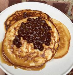 pancakes with raisins and syrup on a white plate