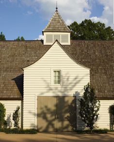 a white barn with a brown shingled roof