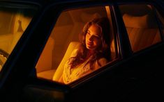 a woman sitting in the passenger seat of a car looking out the window at something