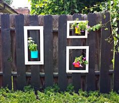 three frames with flowers in them are hanging on a fence