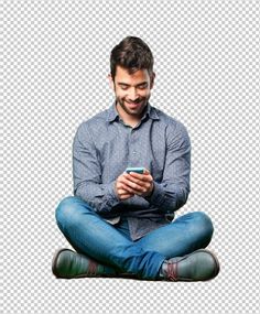 a man sitting cross legged on the floor looking at his cell phone and smiling while he looks down