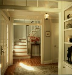 an open door leading to a hallway with stairs and a table on the floor in front of it