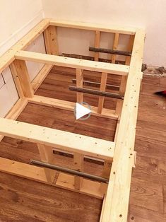 an unfinished bed frame is being built in a room with hard wood flooring and white walls