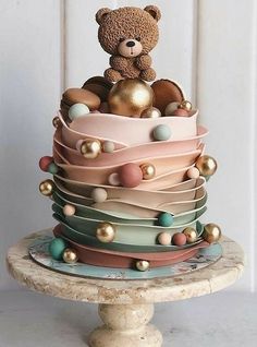 a teddy bear sitting on top of a multi layered cake with balls and pearls around it