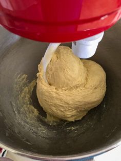 a red mixer mixing dough in a metal bowl