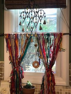 a kitchen window decorated with colorful ribbons and jewelry hanging from it's valance