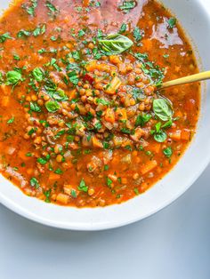 a white bowl filled with soup and garnished with fresh herbs on the side