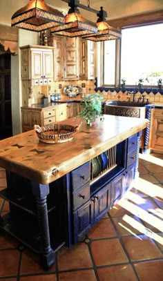 an island in the middle of a kitchen with lights hanging from it's ceiling