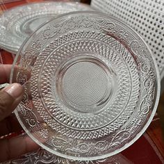 a person holding a clear glass plate on top of a table