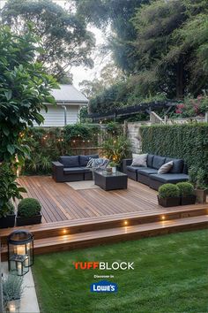 an outdoor deck with couches and potted plants next to it, surrounded by greenery