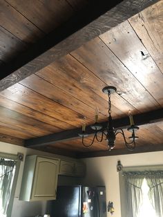 a chandelier hanging from the ceiling in a kitchen with wood paneling on the walls