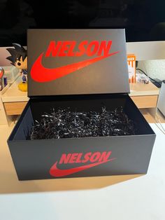 the box is full of black ashs and has a red logo on it that says nelson