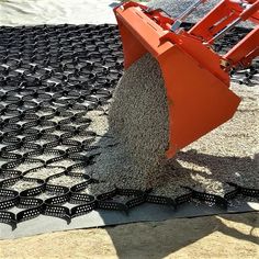 a machine that is sitting on top of some gravel and dirt covering the ground with it's front end