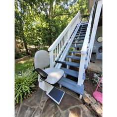 a white chair sitting on top of a stone floor next to a set of stairs