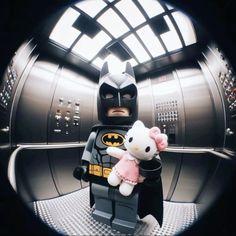 a lego batman and hello kitty doll are posed in front of a round window with the light shining on them