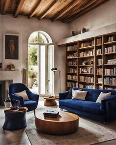 a living room filled with blue couches and bookshelves next to a fire place