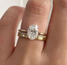 a woman's hand with a gold ring and a diamond engagement ring on it