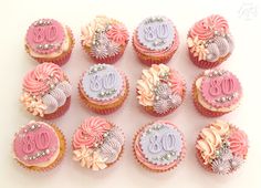 twelve cupcakes decorated with pink and purple frosting