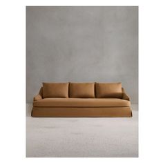 a tan couch sitting on top of a white floor next to a gray wall with no one in it