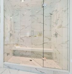 a white marble bathroom with glass shower doors