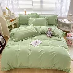 a teddy bear sitting on top of a green comforter