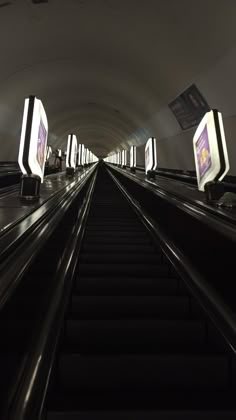 an escalator in a subway station with lots of lights